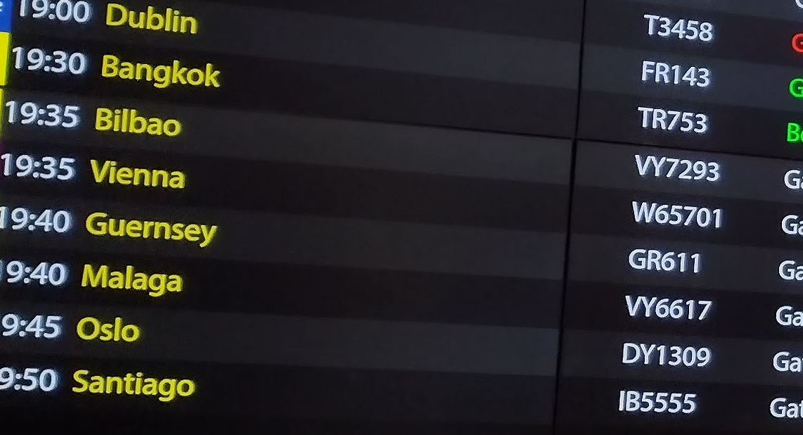 Airport departure board displaying flight destinations, times, and flight numbers